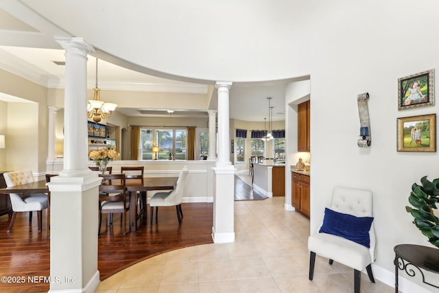 dining area with light tile patterned floors, baseboards, ornamental molding, and ornate columns