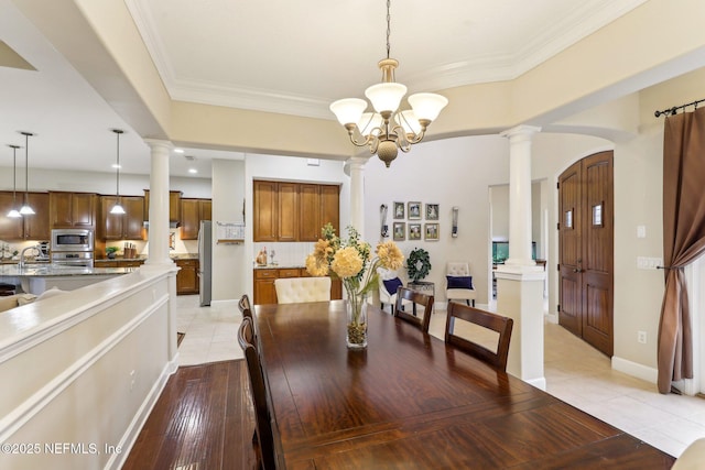 dining area with light tile patterned floors, decorative columns, an inviting chandelier, and ornamental molding