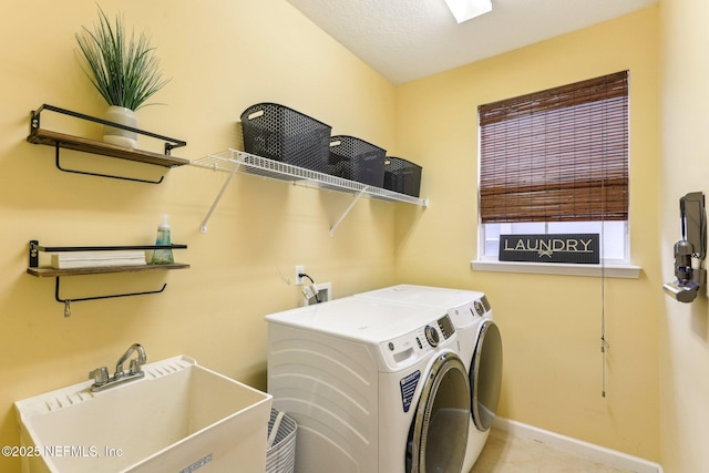 laundry room with a sink, baseboards, separate washer and dryer, and laundry area