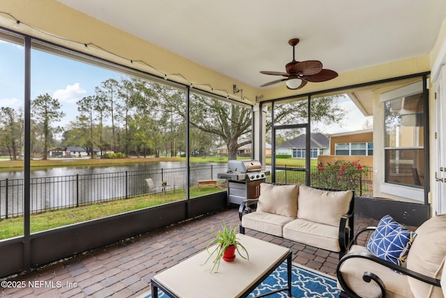 sunroom / solarium featuring ceiling fan and a water view