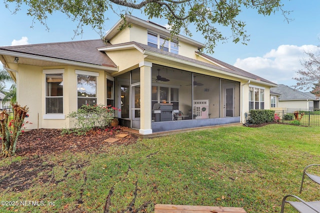 back of house featuring stucco siding, a shingled roof, fence, a yard, and a sunroom