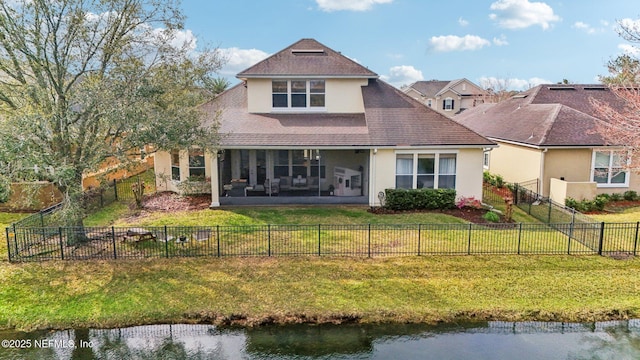 rear view of property featuring stucco siding, a lawn, a fenced backyard, and a sunroom