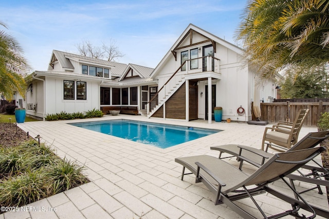 back of house with fence, a sunroom, a fenced in pool, board and batten siding, and a patio area