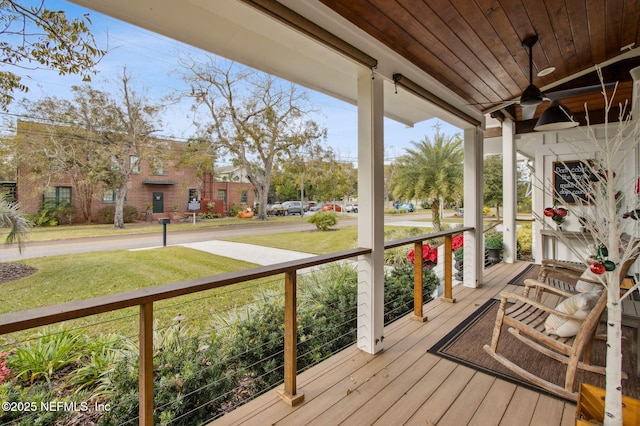 wooden terrace featuring a porch, a lawn, and a ceiling fan