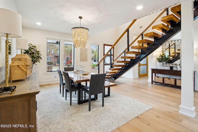 dining space featuring stairway, recessed lighting, wood finished floors, and an inviting chandelier