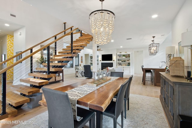 dining room with stairway, a fireplace, visible vents, and an inviting chandelier