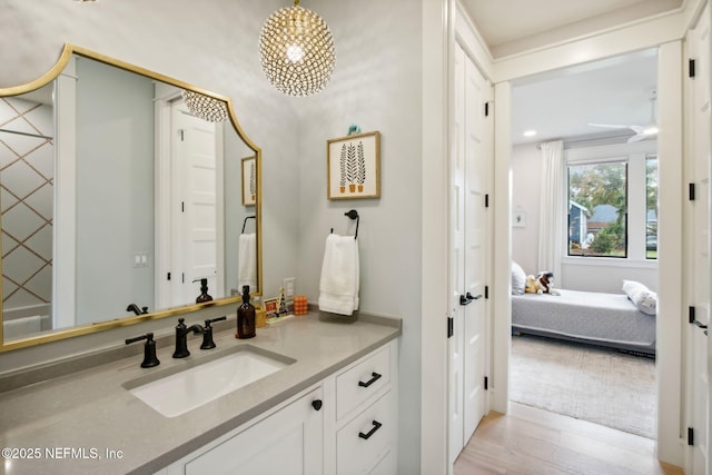 ensuite bathroom with ensuite bath, wood finished floors, and vanity