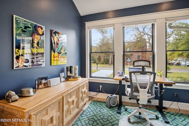 office space featuring baseboards, vaulted ceiling, and wood finished floors