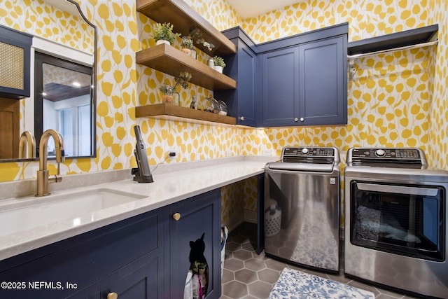 clothes washing area with washing machine and dryer, cabinet space, a sink, and wallpapered walls