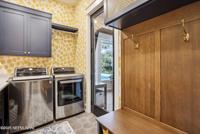 washroom featuring tile patterned flooring, cabinet space, washer and clothes dryer, and wallpapered walls