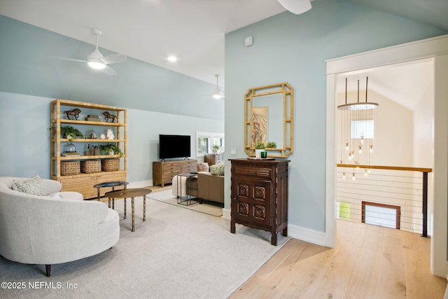 living room with vaulted ceiling, ceiling fan, baseboards, and wood finished floors