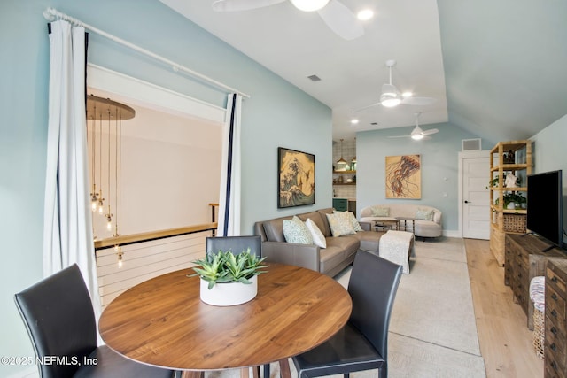 dining room featuring light wood-style floors, vaulted ceiling, visible vents, and ceiling fan