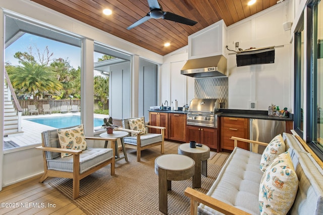 interior space with a ceiling fan, lofted ceiling, wood ceiling, and a sink