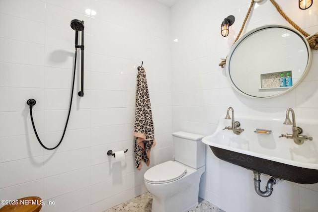 bathroom with a sink, tile walls, toilet, and speckled floor