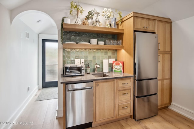 kitchen with lofted ceiling, light wood-style flooring, appliances with stainless steel finishes, open shelves, and a sink