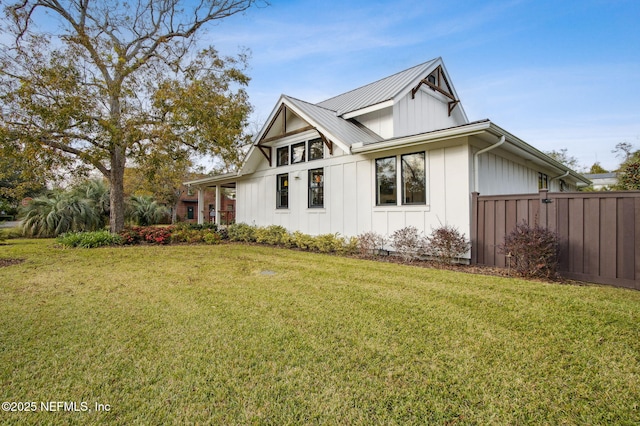 exterior space with metal roof, a front lawn, board and batten siding, and fence