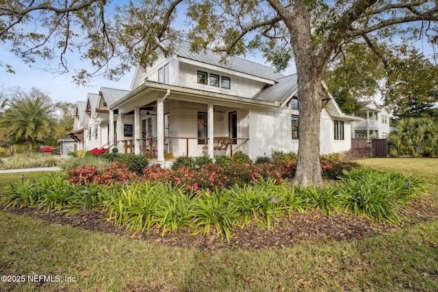 view of front of home with metal roof, a porch, and a front lawn