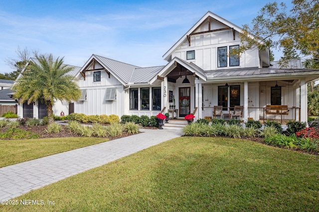 modern farmhouse with covered porch, metal roof, board and batten siding, and a front yard