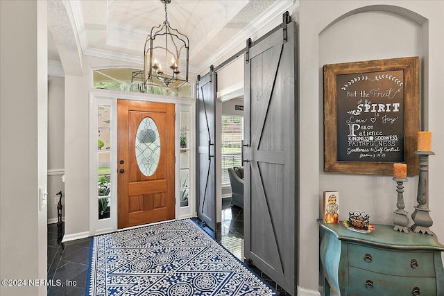 foyer entrance with a tray ceiling, crown molding, a barn door, dark tile patterned flooring, and baseboards