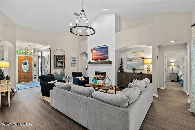 living room with a chandelier, a fireplace, high vaulted ceiling, and dark wood-style floors