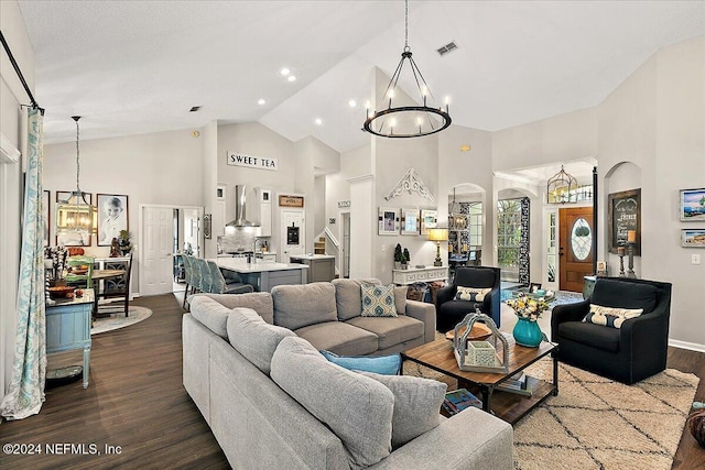 living area featuring visible vents, dark wood-style floors, stairway, an inviting chandelier, and high vaulted ceiling