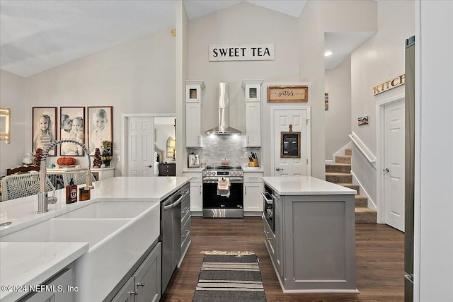 kitchen with stainless steel appliances, gray cabinetry, a sink, and wall chimney exhaust hood