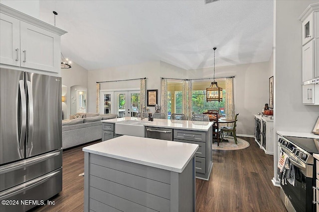 kitchen featuring dark wood-style floors, a center island, vaulted ceiling, stainless steel appliances, and gray cabinetry