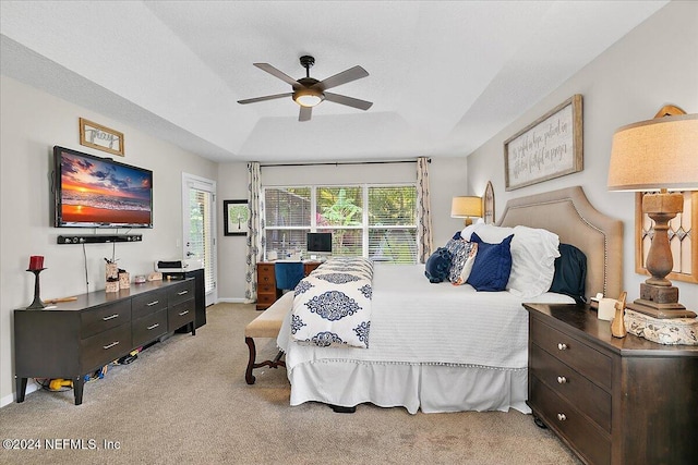 bedroom with baseboards, a raised ceiling, a ceiling fan, and light colored carpet