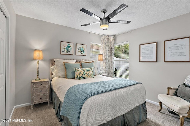 carpeted bedroom with ceiling fan, baseboards, and a textured ceiling