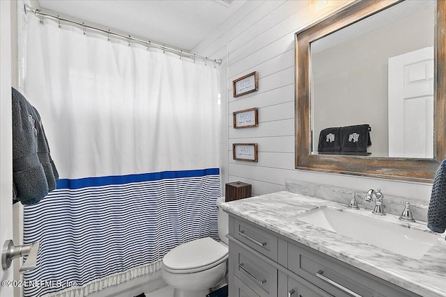 bathroom featuring toilet, wood walls, vanity, and a shower with curtain