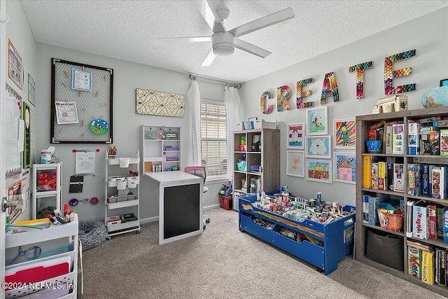 recreation room with a textured ceiling, ceiling fan, carpet flooring, and baseboards