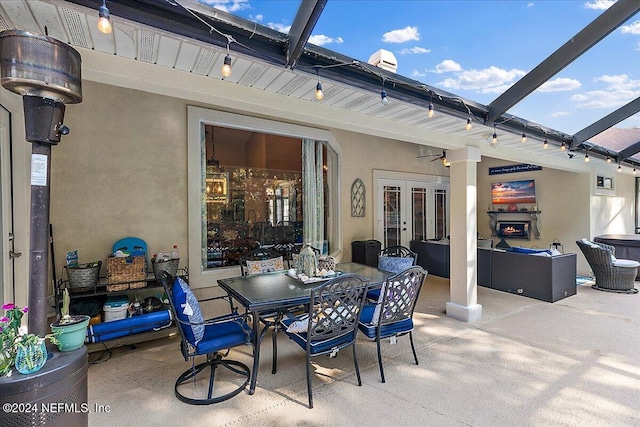 view of patio with glass enclosure, outdoor dining area, a ceiling fan, and french doors