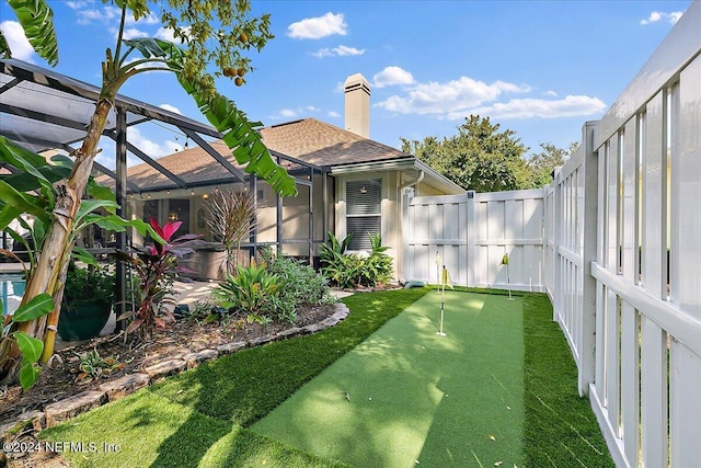 view of yard featuring glass enclosure and fence