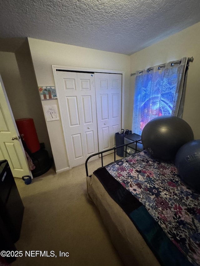 carpeted bedroom featuring a textured ceiling and a closet