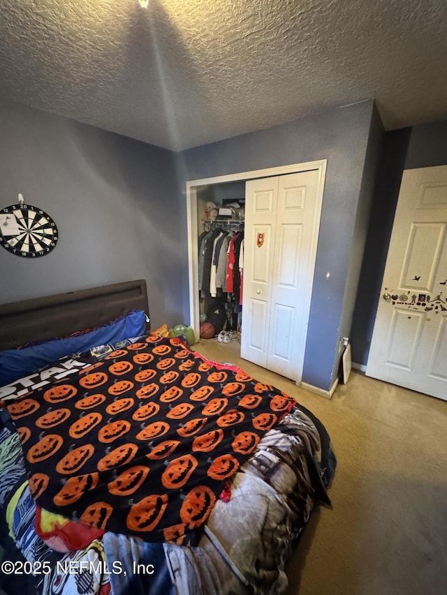 bedroom with a textured ceiling, carpet floors, a closet, and baseboards