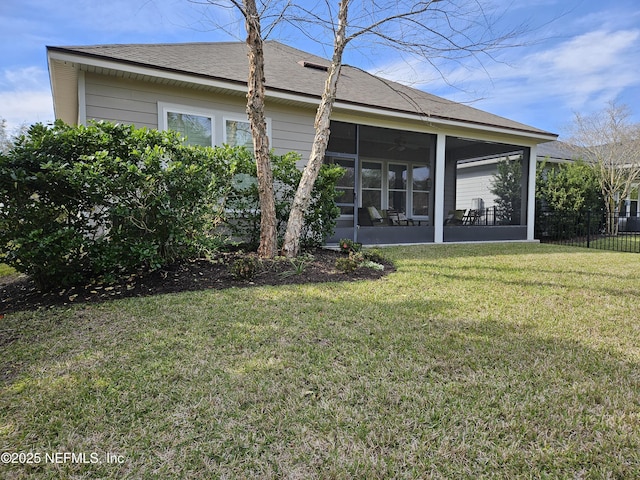 back of house featuring a shingled roof, fence, a yard, and a sunroom