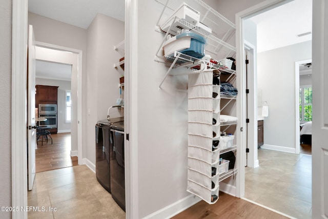 walk in closet with washing machine and dryer and light wood-type flooring