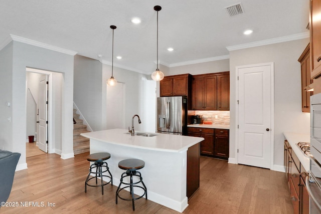 kitchen featuring visible vents, light wood-style flooring, stainless steel refrigerator with ice dispenser, a sink, and decorative backsplash