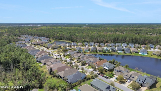 drone / aerial view with a residential view, a wooded view, and a water view