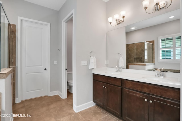 full bath featuring a sink, tiled shower, toilet, and an inviting chandelier