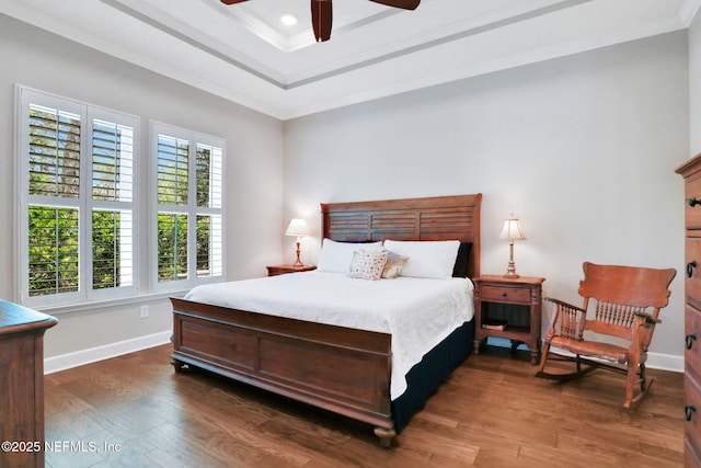 bedroom with a raised ceiling, ornamental molding, recessed lighting, baseboards, and dark wood-style flooring