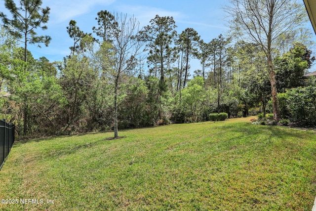 view of yard with a wooded view and fence