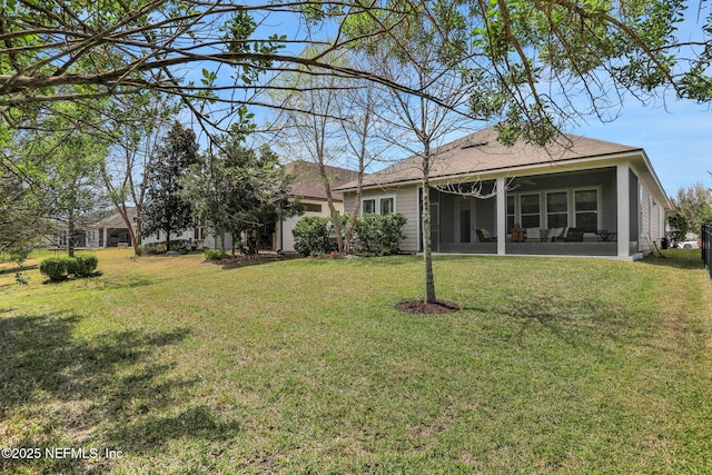 rear view of house featuring a yard, a sunroom, and a shingled roof