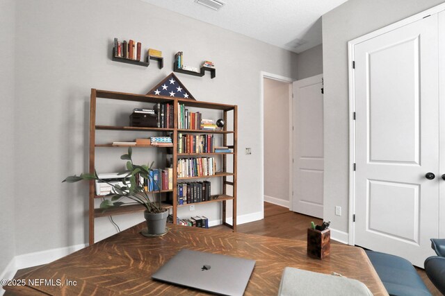 home office with visible vents, baseboards, and wood finished floors