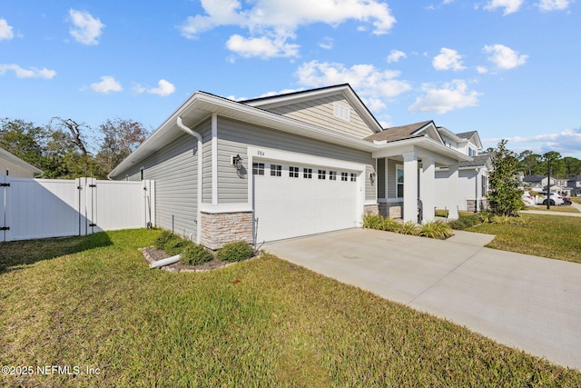 view of front of property with an attached garage, concrete driveway, stone siding, a gate, and a front yard