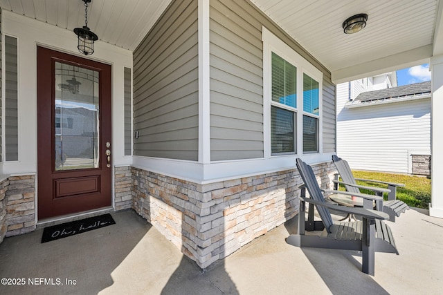 view of exterior entry with stone siding and a porch