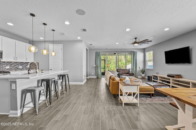 living room featuring recessed lighting, visible vents, wood tiled floor, ceiling fan, and baseboards