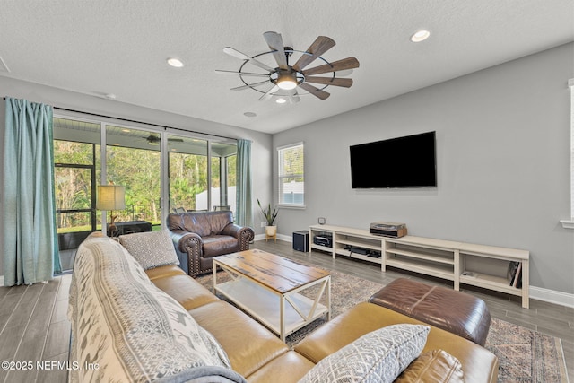 living area with a textured ceiling, wood finish floors, a ceiling fan, and baseboards