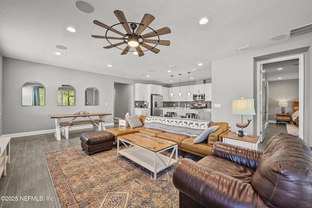 living room featuring baseboards, visible vents, dark wood-type flooring, a textured ceiling, and recessed lighting