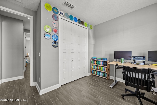 office space featuring baseboards, visible vents, a textured ceiling, and wood finish floors